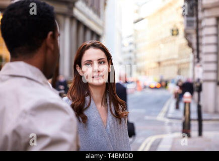 Millennial business colleagues standing on a street in London having a conversation, close up Stock Photo