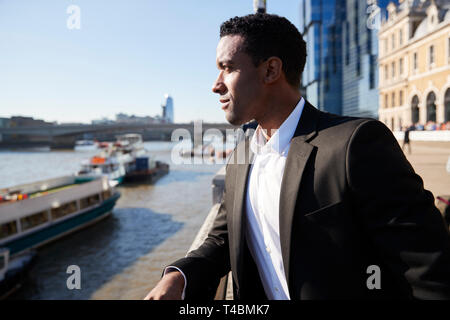 Young back businessman standing at the Thames riverside in the city of London admiring the view, close up Stock Photo