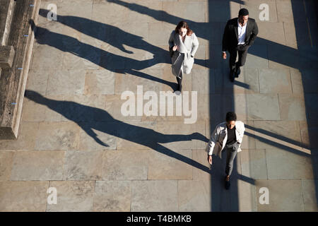 Aerial view of three city workers walking on a sunny urban street, horizontal Stock Photo