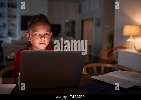Pre-teen Hispanic boy sitting at dining table doing his homework using a laptop computer, close up Stock Photo