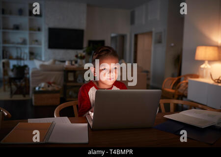 Pre-teen Hispanic boy sitting at dining table doing his homework using a laptop computer, front view Stock Photo