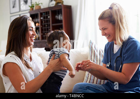 Female healthcare worker visiting a young mum and her infant son at home Stock Photo