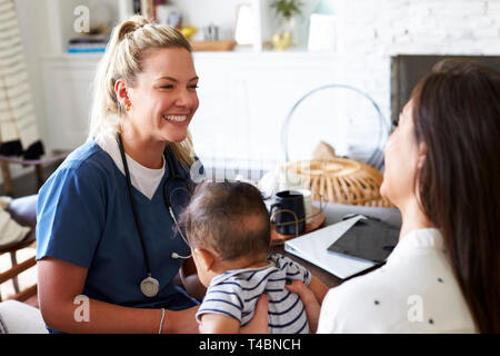 Female healthcare worker visiting a young mum and her infant son at home, close up Stock Photo