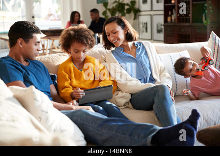 Three generation family family spending time at home in their living room, parents and young kids in the foreground, grandparents in the background, selective focus