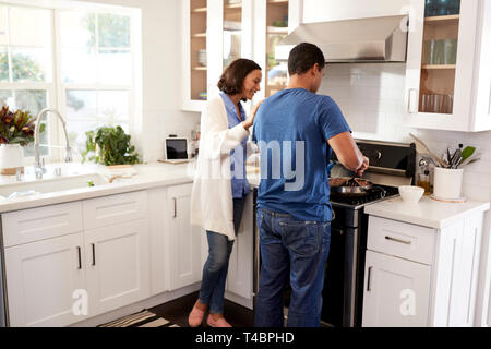 Back view of young couple standing in the kitchen preparing food together Stock Photo