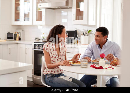 Young couple sitting at the table in their kitchen eating a romantic meal together, selective focus Stock Photo