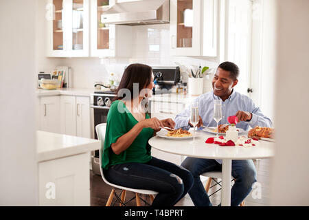 Middle aged mixed race couple eating a romantic meal together in their kitchen, close up Stock Photo
