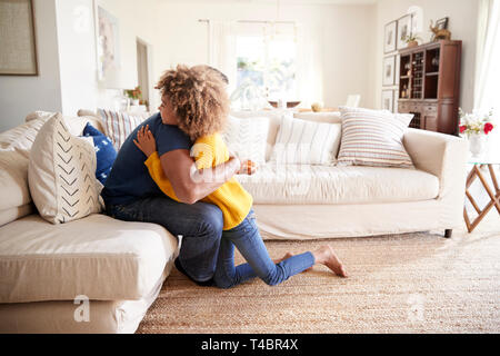 Pre-teen girl hugging her father in sitting room after giving him a handmade gift, side view Stock Photo