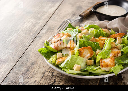 Caesar salad with lettuce,chicken and croutons on wooden table. Copyspace Stock Photo
