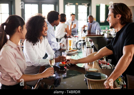 Bartender Serving Two Businesswomen Meeting For After Works Drinks Stock Photo