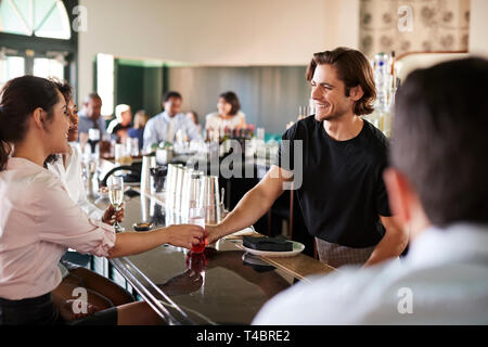 Bartender Serving Two Businesswomen Meeting For After Works Drinks Stock Photo