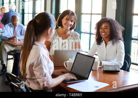 Businesswomen Having Informal Meeting Around Table In Coffee Shop Stock Photo