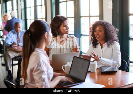 Businesswomen Having Informal Meeting Around Table In Coffee Shop Stock Photo