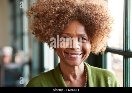 Portrait Of Smiling Senior Woman Sitting In Restaurant Stock Photo