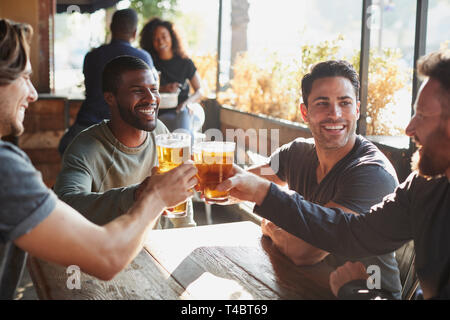 Group Of Male Friends Meeting In Sports Bar Making Toast Together Stock Photo