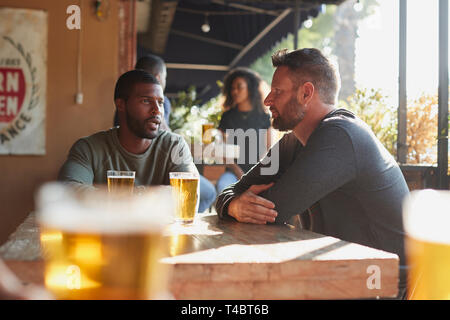 Two Male Friends Meeting In Sports Bar Enjoying Drink Before Game Stock Photo