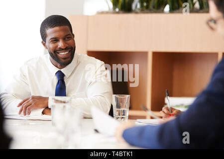 Two Businessmen Sitting Around Table Meeting In Modern Open Plan Office Stock Photo