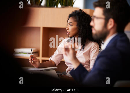 Businesswoman Making Notes Sitting At Table Meeting With Colleagues In Modern Office Stock Photo