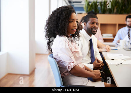 Businesswoman With Colleagues Sitting At Table Listening To Presentation In Modern Office Stock Photo