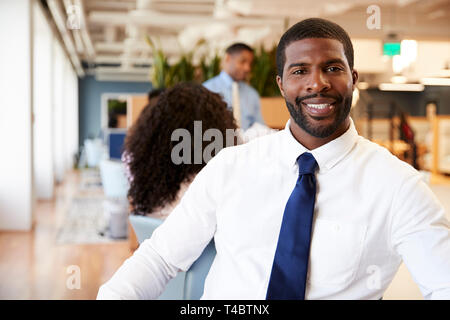 Portrait Of Businessman In Modern Office With Colleagues Meeting Around Table In Background Stock Photo