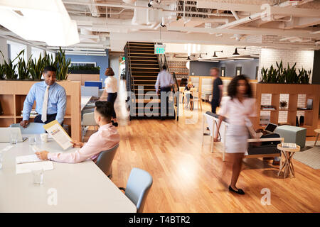 Interior View Of Modern Open Plan Office With Blurred Businessmen And Businesswomen Stock Photo