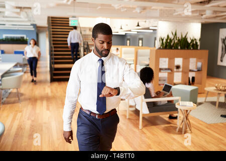 Businessman Walking Through Modern Office Checking Health Data On Smart Watch Stock Photo