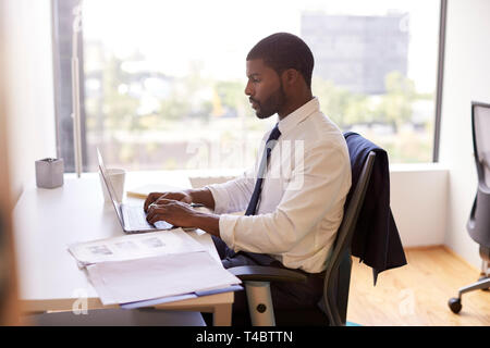 Businessman Sitting At Desk Working On Laptop In Modern Office Stock Photo