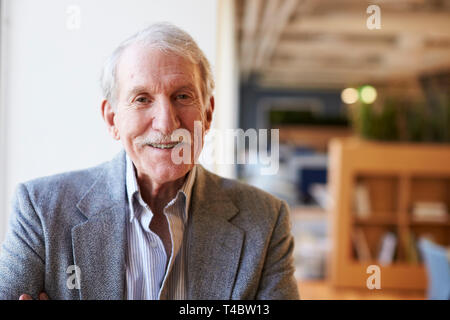 Portrait Of Smiling Senior Businessman In Modern Office Standing By Window Stock Photo