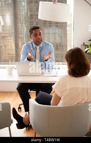 Male Financial Advisor In Modern Office Sitting At Desk Meeting Female Client Stock Photo