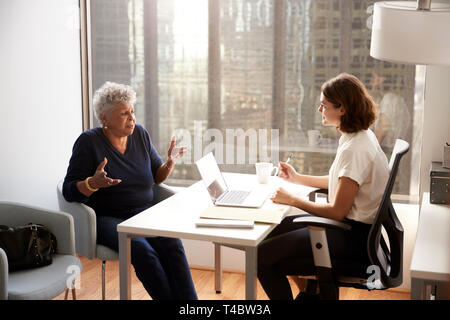 Senior Woman Having Consultation With Female Doctor In Hospital Office Stock Photo
