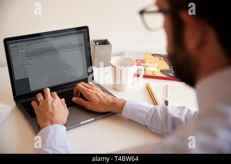 Businessman Sitting At Desk Working On Laptop In Modern Office Stock Photo
