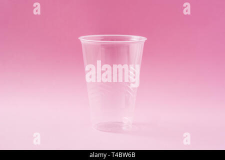 Disposable waste plastic glass on pink background. Stock Photo