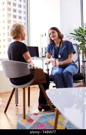 Senior Woman Having Consultation With Female Doctor Wearing Scrubs In Hospital Office