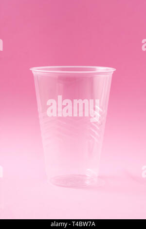 Disposable waste plastic glass on pink background. Stock Photo