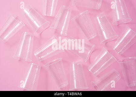 Disposable waste plastic glasses on pink background. Top view Stock Photo
