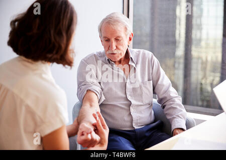 Senior Man Being Vaccinated With Flu Jab By Female Doctor In Hospital Office Stock Photo