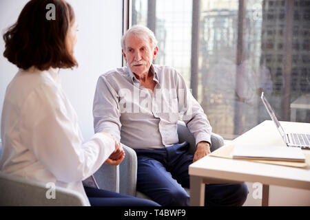 Female Doctor In Office Reassuring Senior Man Patient And Holding His Hands Stock Photo