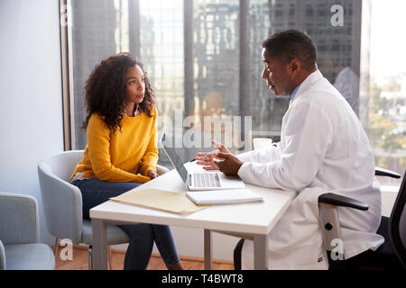 Serious Woman Having Consultation With Male Doctor In Hospital Office Stock Photo