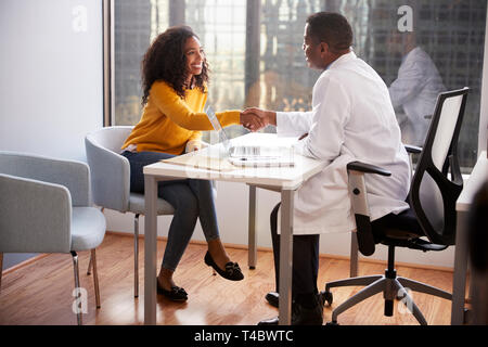 Woman Shaking Hands With Male Doctor In Hospital Office Consultation Stock Photo