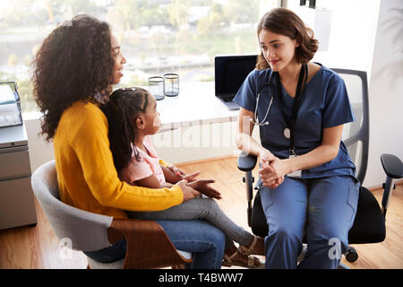 Mother And Daughter Having Consultation With Female Pediatrician Wearing Scrubs In Hospital Office Stock Photo