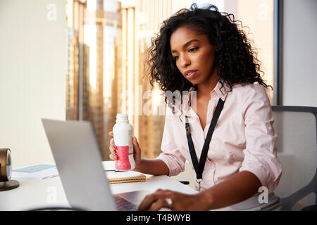 Busy Businesswoman With Laptop Sitting At Desk Having Protein Shake For Working Lunch Stock Photo