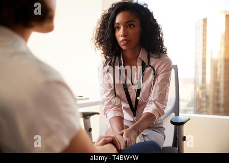 Female Doctor In Office Reassuring Woman Patient And Holding Her Hands Stock Photo