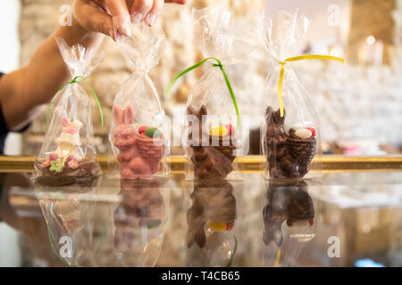 16 April 2019, Bavaria, Schweinfurt: Easter bunnies made of different types of chocolate, various colours and representations are standing on a table in the Chocolaterie Molina, a chocolate factory. Easter is also a festival for the confectionery industry. But chocolate manufacturers have to face up to the increased demands of consumers.  (for dpa: "Chocolate manufacturer between tradition and trends"). Photo: Daniel Karmann/dpa Stock Photo