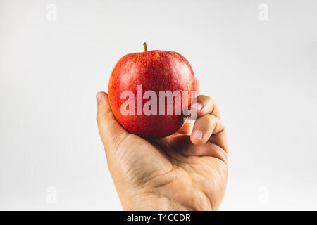 hand holding a red apple fruit against white background Stock Photo