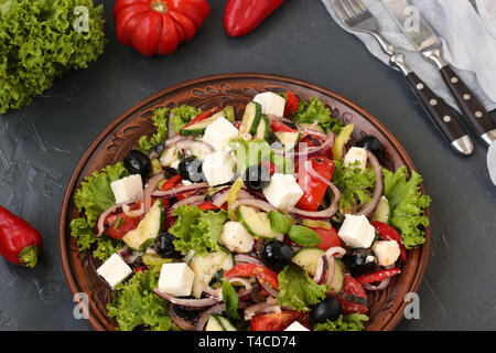 Healthy salad of lettuce, tomato, red onion, pepper, soft cheese, olives, basil, cucumbers, with olive oil and lemon juice. Greek salad Stock Photo