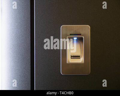closeup fingerprint sensor on modern armored metallic black door and blue light led indicator Stock Photo