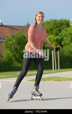 Young woman rollerblading on a small road Stock Photo