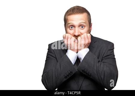 Closeup portrait of nervous handsome businessman with facial beard in black suit standing, biting his nails and looking at camera with worried face. i Stock Photo