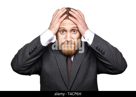 Closeup portrait of sad handsome businessman with facial beard in black suit standing holding his head and looking at camera with sorrow hopeless face Stock Photo