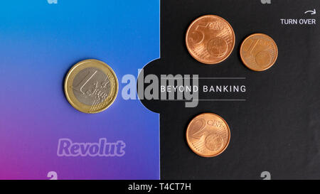 New York, USA - March 15, 2019: Revolut card packaging with euro coins on top. Revolut logo on purple to blue gradient and the slogan 'Beyond Banking' Stock Photo